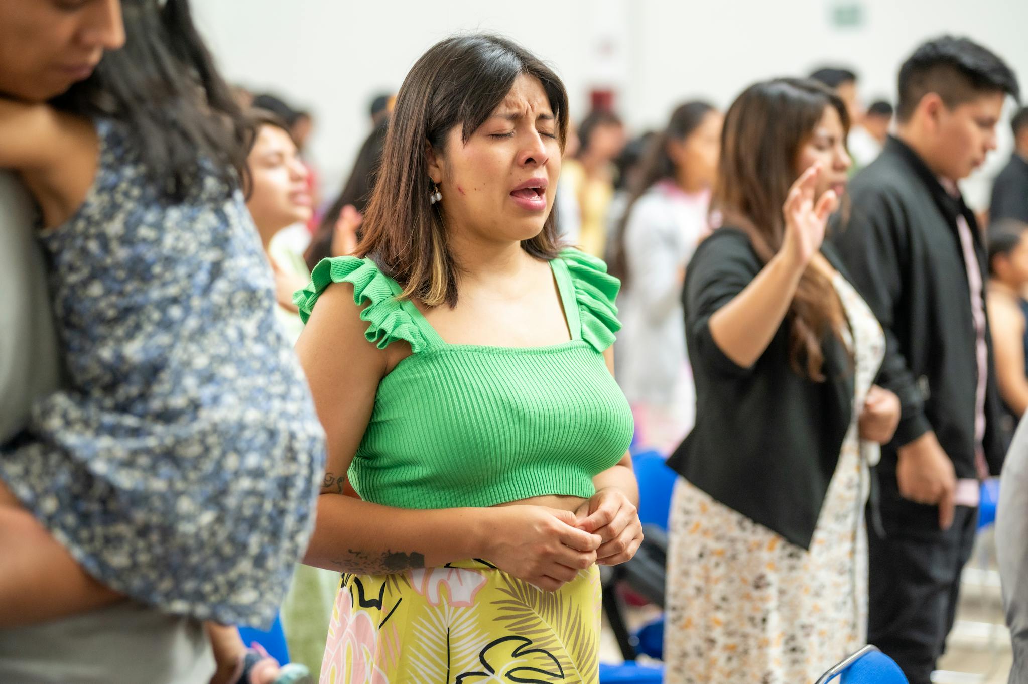 A diverse group of people worshiping indoors in Ciudad de México, expressing devotion and community.