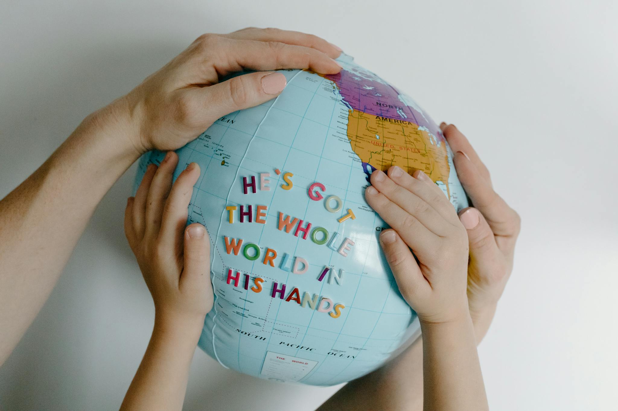 Hands of different ages holding a globe with the text 'He's got the whole world in His hands.'